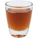 An Arcoroc shot glass filled with brown liquid on a white background.