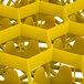 A yellow plastic Vollrath TR18J glass rack with 12 compartments and many holes.