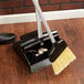 An Unger Ergo angled lobby broom and dustpan on a wood floor.