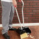 A man using an Unger Ergo angled lobby broom and dust pan.