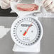 A gloved hand weighing meat on a Cardinal Detecto portion scale.