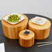 A set of three round bamboo risers with wooden containers of food on top.