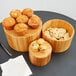 A table with a group of wood containers holding muffins and cookies.