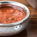 An American Metalcraft stainless steel Moroccan hammered bowl of salsa on a table.