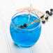 A blue drink in an Arcoroc Salto rocks glass with a straw and a small umbrella.