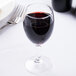An Arcoroc wine glass filled with red wine on a table.