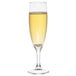 An Arcoroc champagne flute filled with yellow liquid.