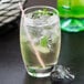 An Arcoroc highball glass filled with ice, liquid, and a straw.