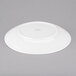 An Arcoroc white porcelain plate with a circular rim on a gray surface.