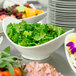 A 10 Strawberry Street Whittier white porcelain serving bowl filled with green salad on a buffet table.