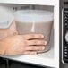 A hand holding a translucent round deli container.