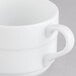 A close-up of a white Arcoroc coffee cup with a handle.