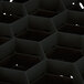 A close-up of a black Vollrath glass rack with hexagon compartments.