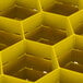 A yellow Vollrath Traex glass rack with square compartments and a hexagonal hole in the middle.