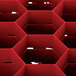 A red plastic Vollrath Traex glass rack with hexagonal compartments.