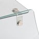 A close-up of a curved glass sneeze guard shelf with metal handles and a metal latch.