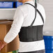 A large black back support belt worn by a person lifting a box.