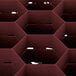 A close up of a red Vollrath Traex glass rack with hexagonal compartments.
