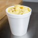 A Dart white foam food container filled with food on a table.