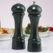 Two green Chef Specialties pepper grinders on a table.