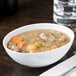 A white 10 Strawberry Street Royal porcelain bowl filled with stew with meat and vegetables.