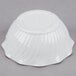 A white Cambro plastic swirl bowl on a gray surface.
