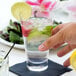 A person holding an Arcoroc Shetland highball glass of water with lime slices.