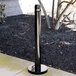 A black Rubbermaid cigarette receptacle on a metal pole.