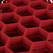A red plastic container with hexagonal compartments and many small holes.