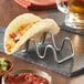 A Tablecraft Taco Taxi holding 2 tacos on a table with a glass of beer.