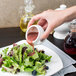 A hand pouring red sauce over a white mini lion head tureen.