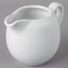 A 10 Strawberry Street Whittier white porcelain creamer with a handle on a gray surface.