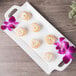 A white rectangular porcelain handled platter with donuts on it.