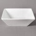 A white square bowl on a gray surface.