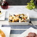 A rectangular white porcelain dish with a plate of food including olives, cheese, and meat.