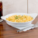 A white china shirred egg dish filled with macaroni and cheese on a table.