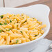 A white china dish filled with macaroni and cheese with parsley on top.