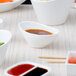 A white bowl with brown liquid in it on a table with bowls of food.