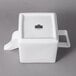 A white square porcelain teapot with a handle.