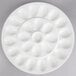 A close-up of a white 10 Strawberry Street porcelain egg platter with a circular design and holes in it.