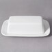 A 10 Strawberry Street white porcelain covered butter dish on a gray surface.