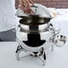 A person holding a Vollrath stainless steel round soup chafer lid.