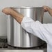 A person using a Vollrath Wear-Ever Classic aluminum stock pot on a stove.