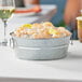 A metal tub filled with shrimp and lemons on a table.