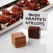 A wooden cube table card holder on a table with bacon wrapped food on sticks.