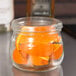 An American Metalcraft condiment mason jar filled with orange slices on a counter.