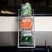 An American Metalcraft glass condiment jar filled with baby carrots on a metal rack.