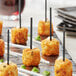 A plate of food with Royal Paper black plastic arrow picks on a table at a catering event.