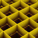 A yellow Vollrath glass rack with square compartments.