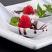 A spoonful of dessert with raspberries and chocolate sauce served in a Thunder Group white melamine Chinese Wonton Soup Spoon.
